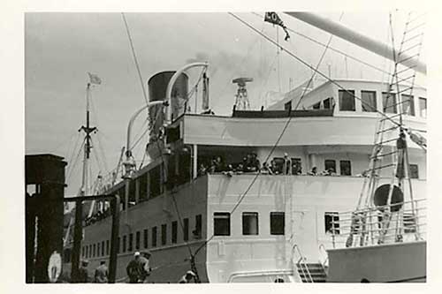 Black and white photo of a ship docked in the harbour.