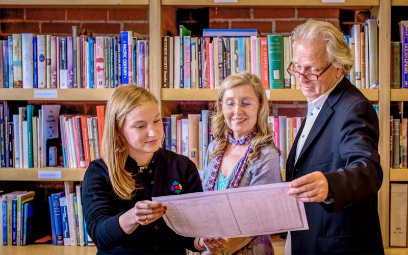 A staff member helps a man and women who are examining documents