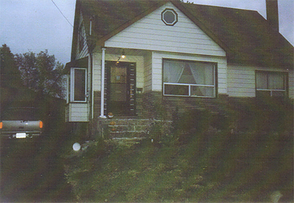 A house at dusk as seen from the end of the driveway, with curious orbs of light appearing.