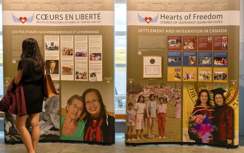 A woman walks by two exhibition panels, displayed in both English and French.