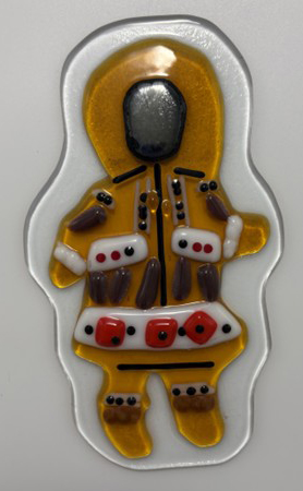 Fused glass piece depicting a figure wearing the ceremonial winter clothing of Indigenous people in the Western Artic, crafted from caribou and sealskin, with squirrel hide embellishments.