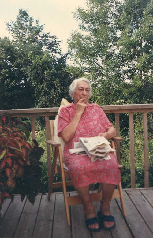 An elderly lady sits on the deck of a ship looking pensive.