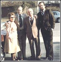 Well-dressed foursome posing for camera in parking lot.