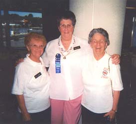 Older Audrey in the middle of two female friends, all wearing white tee shirts.