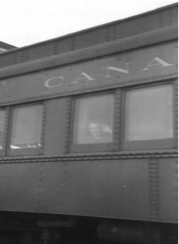 Seated figure, waving from train window.