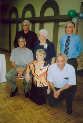 Six family members in a hall decorated with balloons.
