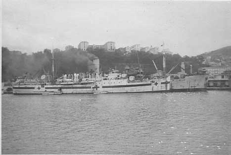 Black and white photo of a ship with smoke coming out of the funnels.