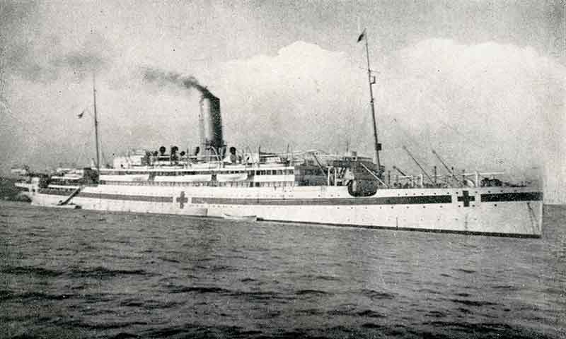 A hospital ship with the familiar red cross symbol, as seen from the dock.