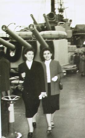 Two women wearing jackets and skirts, walking towards the camera.