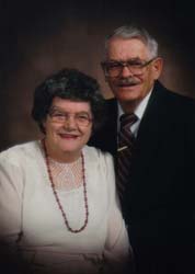 A well-dressed couple pose for a photo.