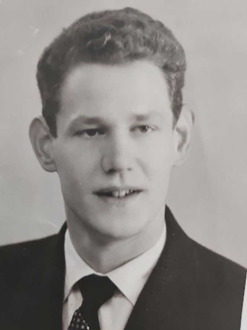 Portrait of a young man, dressed in suit and tie, smiles.