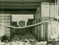 Photograph showing damage to a warehouse where large boxes can be seen.