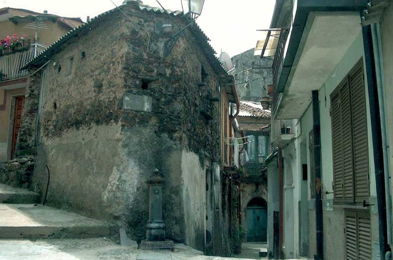 Scene from a cobbled street in Italy showing an old water fountain.