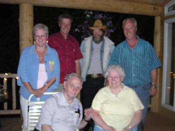Colour photograph showing six adult family members, sitting on a patio.