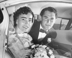 Young married couple sitting in the back of a car on their wedding day.