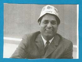 Man in suit and tie, wearing a white hat.