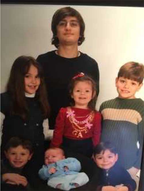 Colourful portrait of seven children, ranging in age from teenager to small baby