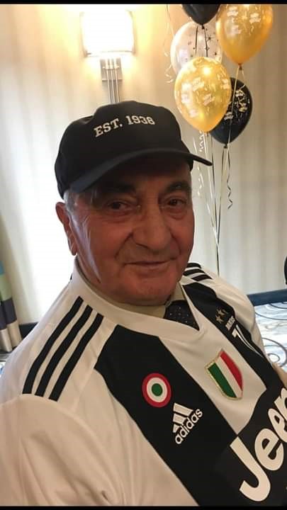 A man smiling with balloons behind him.