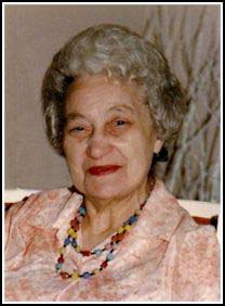 Pearl, older, wearing a peach blouse and a brightly coloured necklace.