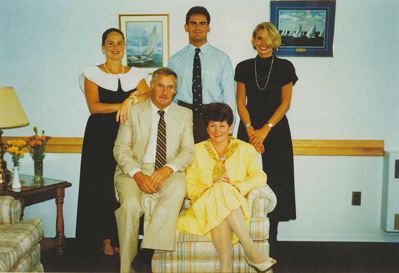 A coloured portrait of a family of five, the mother and father are seated and three adult children stand behind them.