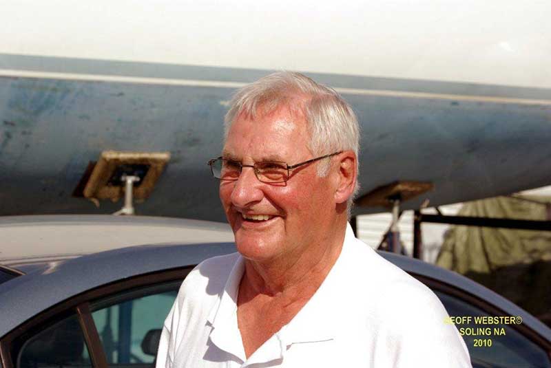 A smiling man with glasses looks off to the side of the camera.