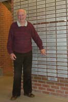 Rudolf as an older man, pointing to his Wall of Honour plaque at Pier 21 Museum.
