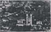 Aerial view of a Hungarian city with a church and its towers visible.