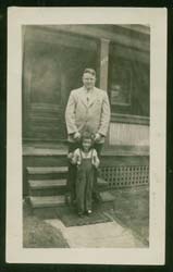 Gerald and his young daughter standing in front of the steps of his house.