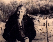 Woman looking at the camera, trees in the background.