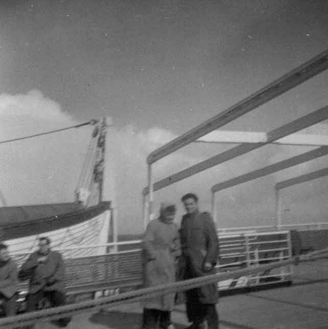 Two people are standing and two sitting on the bench for sun light.