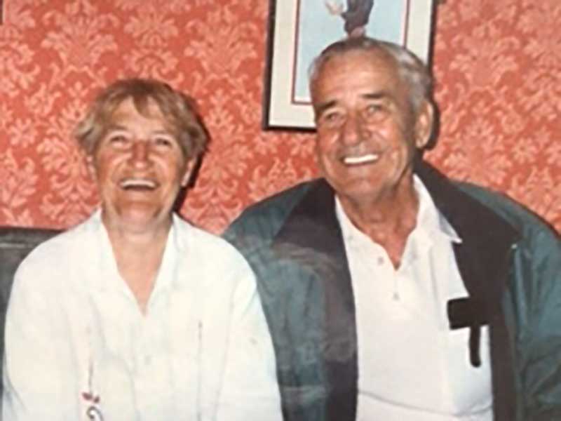 A couple are sitting and smiling for a photo.