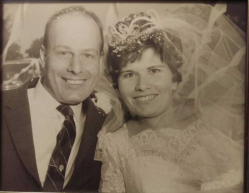 A young married couple smile for the camera on their wedding day.